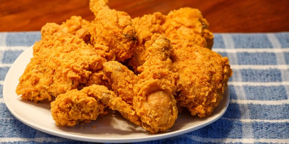 D4XP8J A plate of crispy fried chicken on a blue plaid placemat and a wood table
